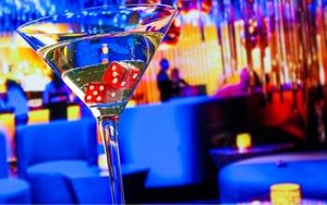 martini glass with lucky red dice inside of it at a blue lit night club lounge